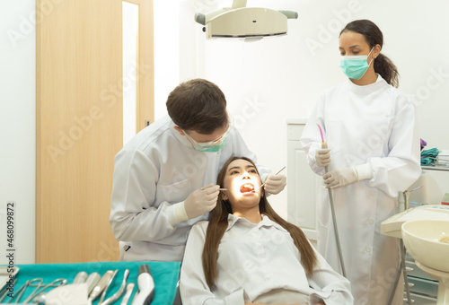 A dentist checking up a woman patient s teeth by using dental mouth mirror at hospital clinic. Teeth check up with dental tools. Doctor. Dentistry  medical and health. People.