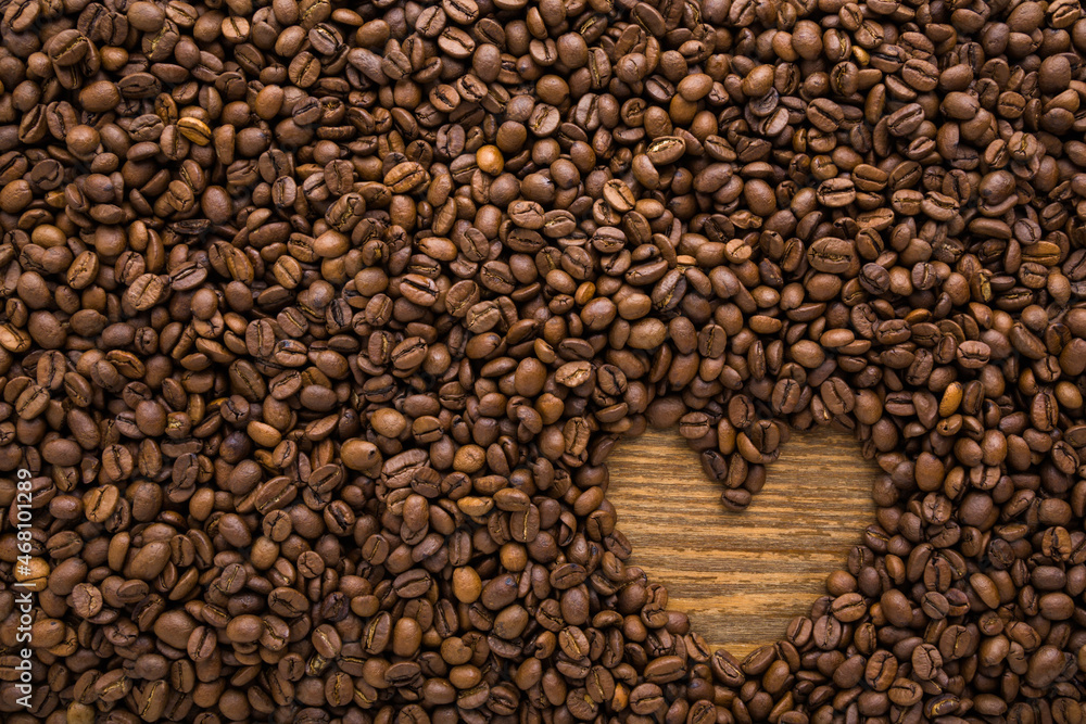 Small heart shape created from fresh dark brown coffee beans. Empty place for text. Closeup. Top down view. Small heart shape created from fresh dark brown coffee beans. Empty place for text. Closeup. Top down view.
