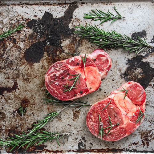 Raw meat  osso buco meat on old metal try with rosemary. Concept for cooking photo