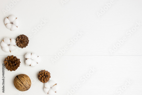Nature cotton flowers and pine cones over the white wooden background. 