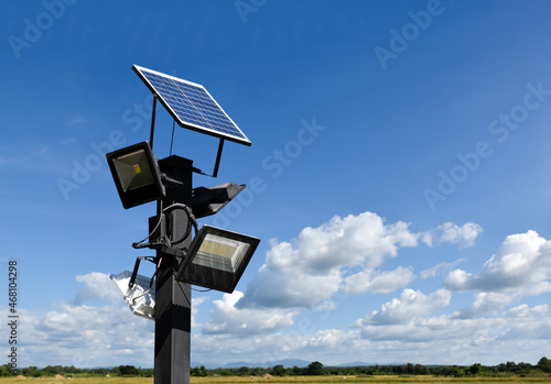 Photovoltaic panel systems and hd floodlights on black metal pole in public park, soft and selective focus.