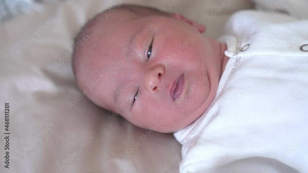 Beautiful little newborn laying on white blanket. Close up view of small cute baby in light cloth. Beautiful little newborn laying on white blanket. Close up view of small cute baby in light cloth.