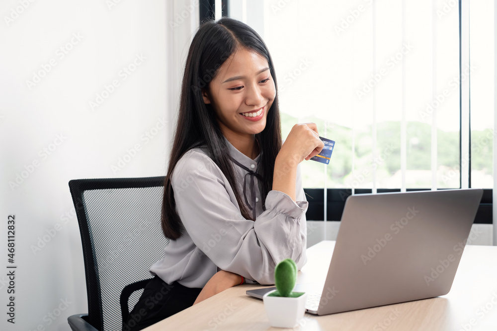 The Asian businesswoman's hand is holding a credit card and using a laptop for online shopping and internet payment in the office The Asian businesswoman's hand is holding a credit card and using a laptop for online shopping and internet payment in the office