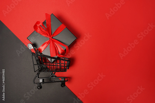 Black Friday sale shopping cart with gift box on red background Fototapeta