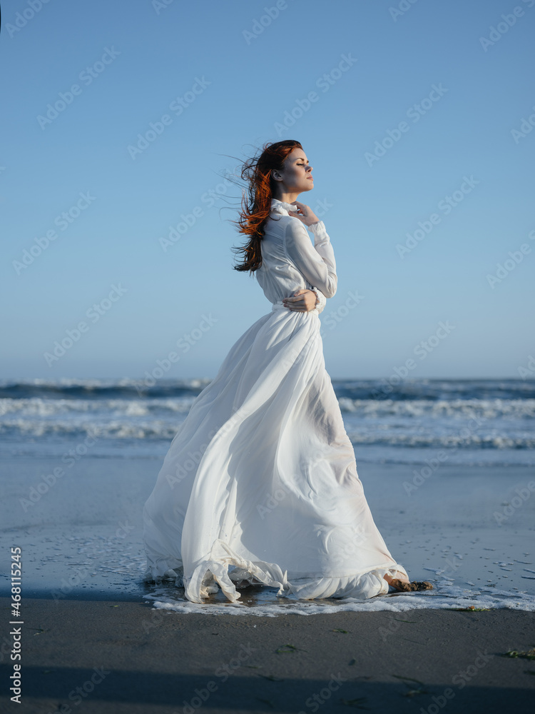 Woman in white dress walking along the beach ocean vacation Woman in white dress walking along the beach ocean vacation