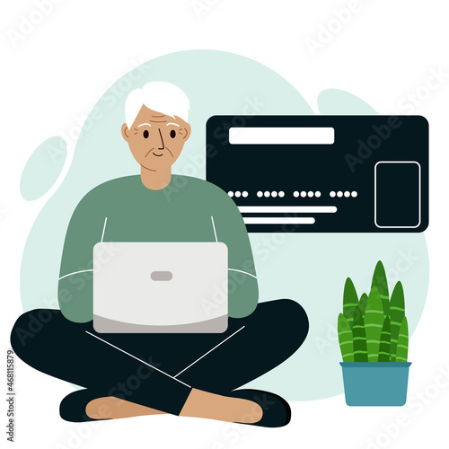 Online payment concept. Close up of a large credit card. The old man sits cross-legged, holding a laptop in his hand.
