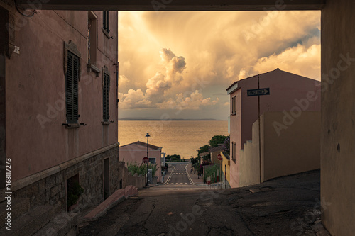 Sonnenuntergang mit tollen leuchtenden Wolken am Himmel in einem kleinen Städtchen am Mittelmeer auf Sardinien, Italien.