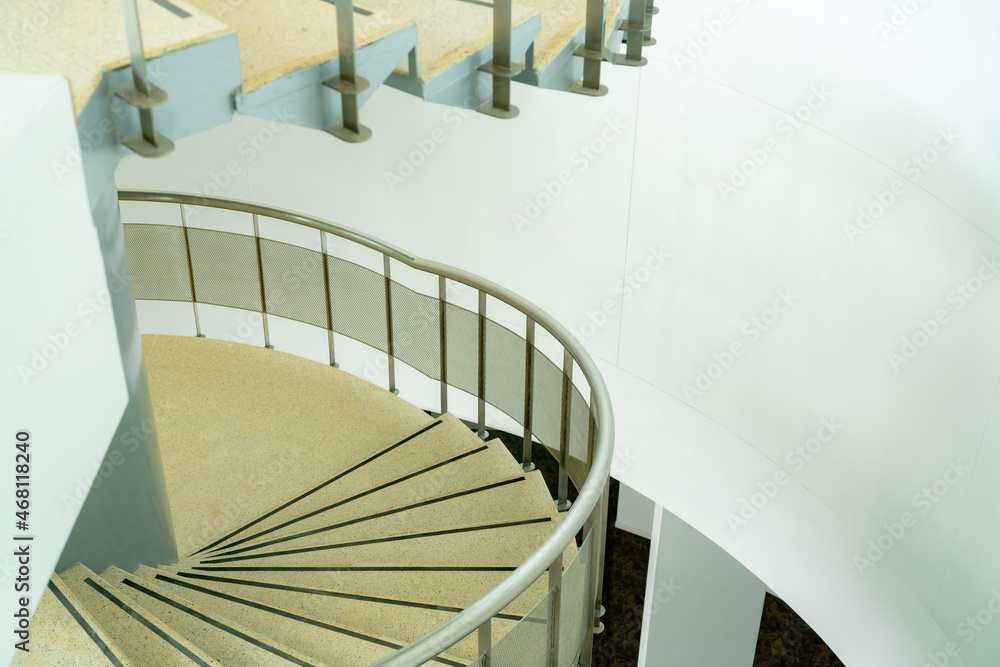 Fototapeta premium The curved steel staircase goes up to the second floor. with stainless steel handrails The stairs are marble.