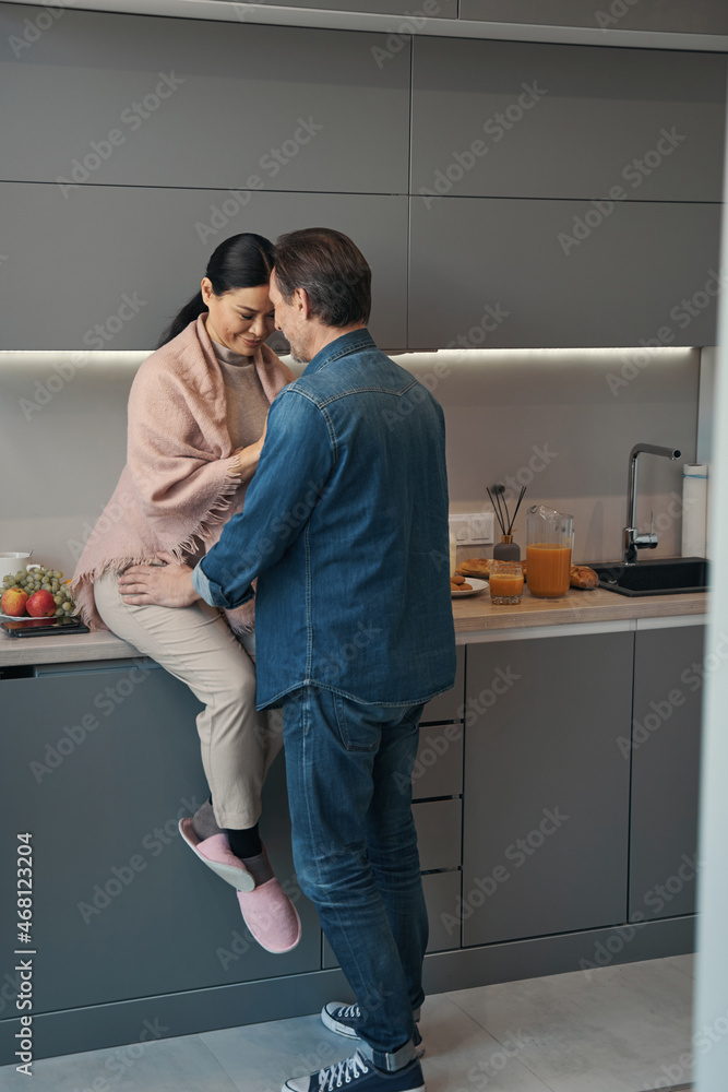 Loving mature couple cuddling during morning in kitchen Loving mature couple cuddling during morning in kitchen