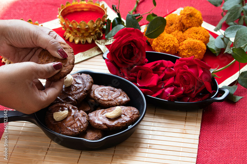 Hands Of Girl Holding Indian Mithai Thekua Thokwa Or Thekuwa Is Made Of Wheat And Meetha Dry Fruits Is Offered to Sun God During Auspicious Chhath Puja Celebrated In Uttar Pradesh Bihar In North India