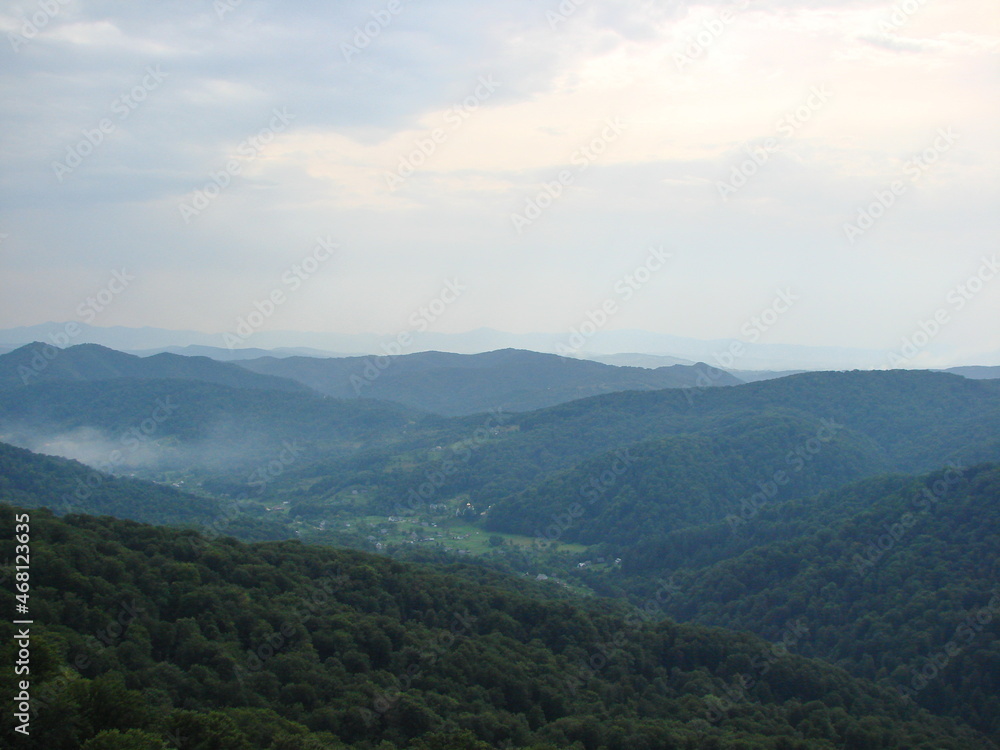 Panorama of cloudy sky over endless mountain ranges covered with a green carpet of Transcarpathian forests.