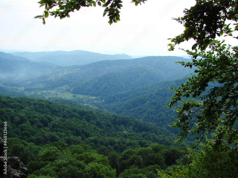 View from the stone top on the soft green carpet of mountain forests through the prism of the evening fog. View from the stone top on the soft green carpet of mountain forests through the prism of the evening fog.