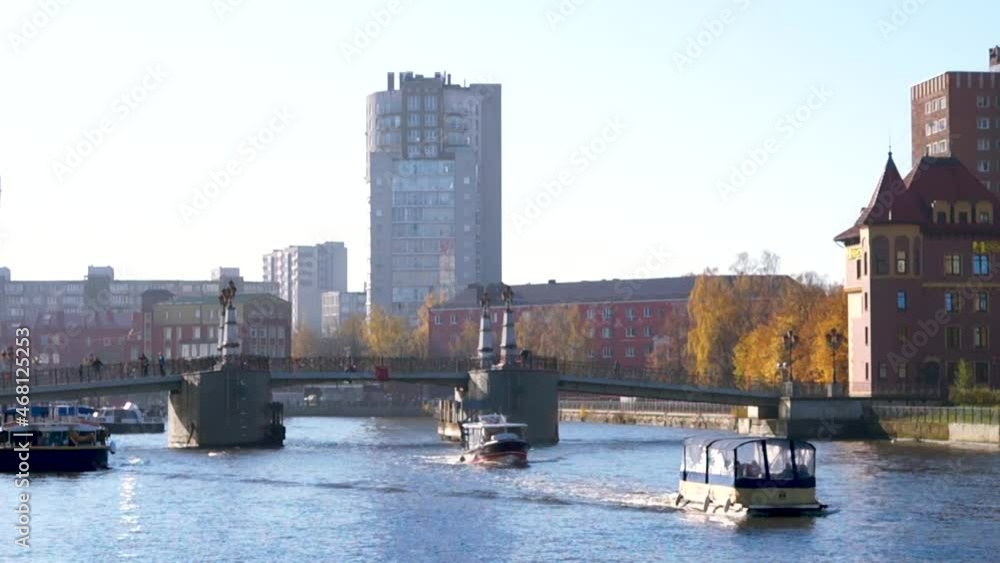 Tourist ship passes on the river. Jubilee Bridge. Old Town. Fish Village - ethnographic and trade and crafts complex. Kaliningrad, Russia, October 25, 2021. Tourist ship passes on the river. Jubilee Bridge. Old Town. Fish Village - ethnographic and trade and crafts complex. Kaliningrad, Russia, October 25, 2021.