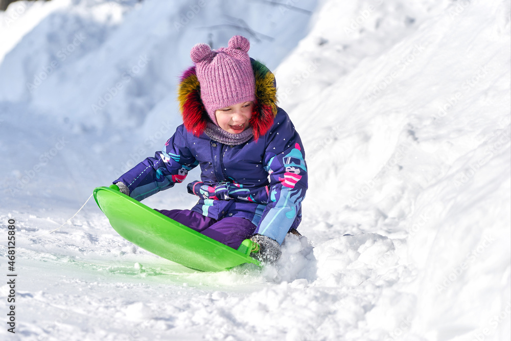 Little girl riding on a sled during winter Little girl riding on a sled during winter
