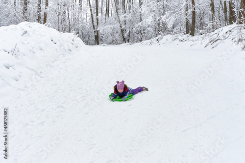 Little girl sledding in the snowy forest