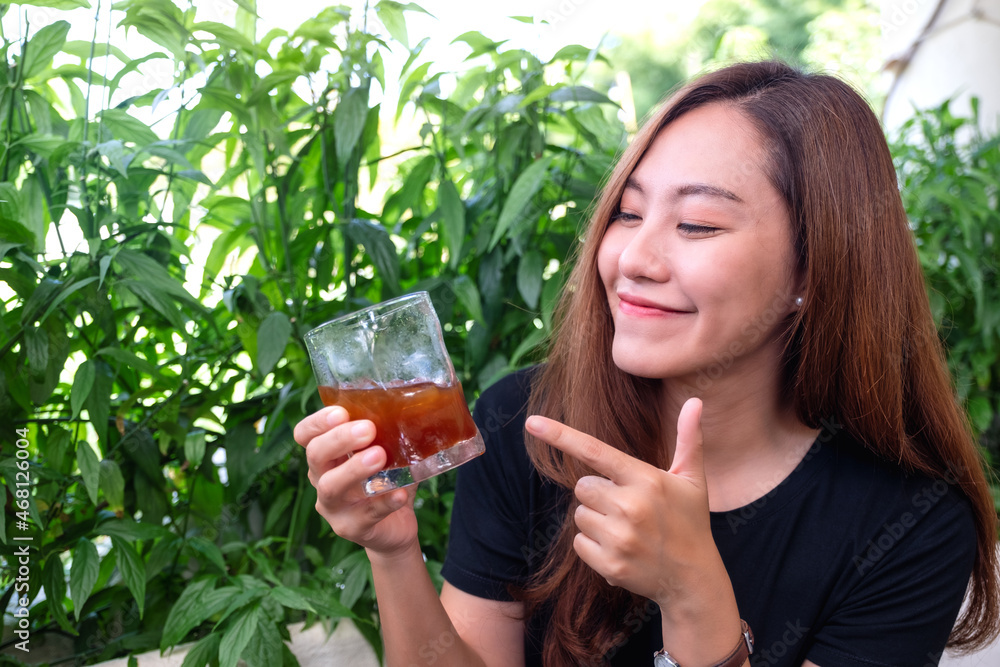 A young asian woman holding and pointing finger at a glass of iced coffee A young asian woman holding and pointing finger at a glass of iced coffee