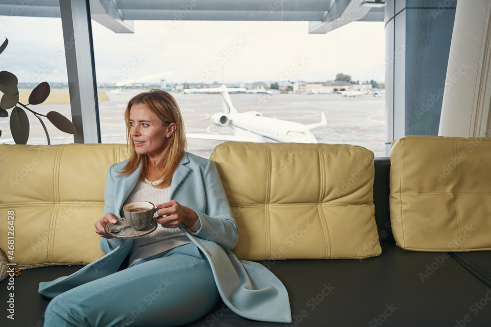 Pleased woman drinking coffee in airport lounge Pleased woman drinking coffee in airport lounge