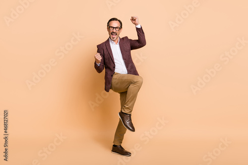 Full length body size view of attractive cheerful crazy man dancing having fun isolated over beige color background