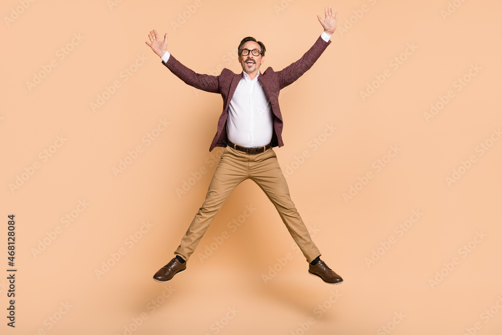 Full length body size view of attractive cheerful carefree man guy jumping having fun isolated over beige color background Full length body size view of attractive cheerful carefree man guy jumping having fun isolated over beige color background