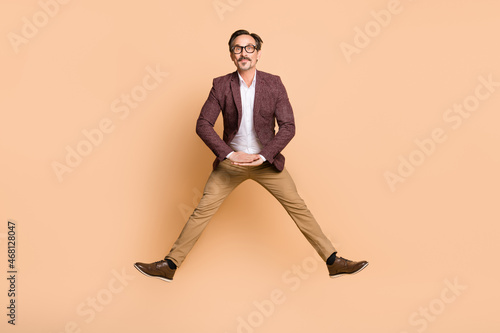Full length body size view of attractive funky man guy executive director jumping having fun isolated over beige color background