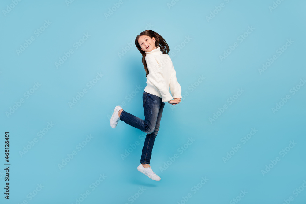 Photo of charming dreamy student girl wear white sweater smiling jumping high isolated blue color background