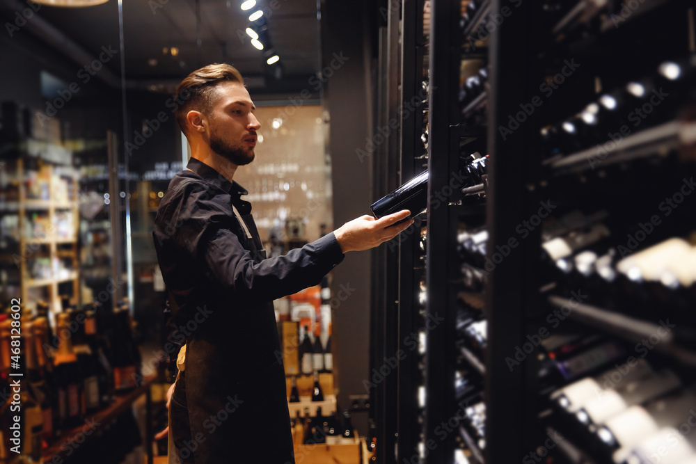 Bartender sommelier man with wine bottle near rack store restaurant with exquisite drinks Bartender sommelier man with wine bottle near rack store restaurant with exquisite drinks