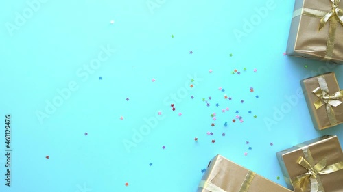 festive multicolored sparkles in the form of stars fall on a blue background with golden gifts