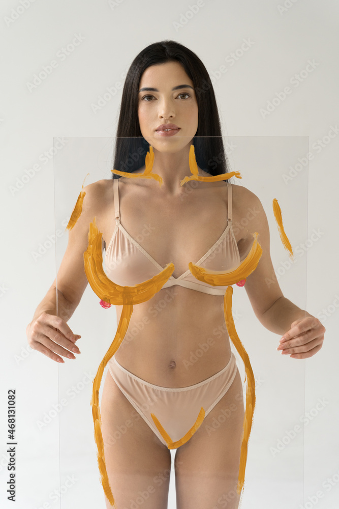 Fototapeta premium Woman holding transparent glass with drawing contours of the figure in front of her body