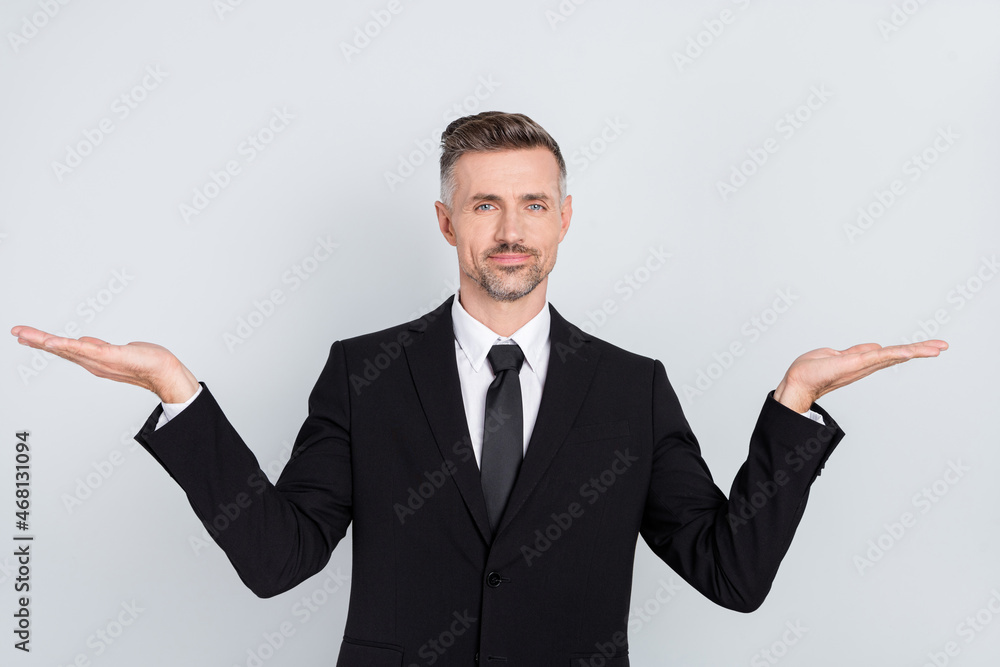 Photo of pretty confident mature broker dressed black suit compare arms empty space isolated grey color background Photo of pretty confident mature broker dressed black suit compare arms empty space isolated grey color background