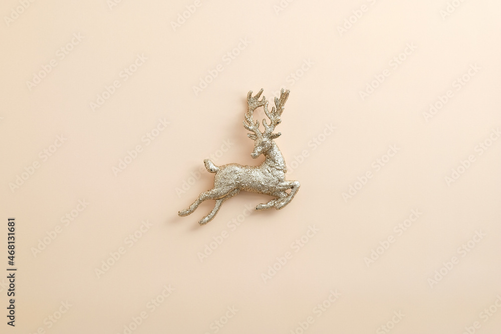 Obraz premium Christmas golden reindeer decoration on pastel beige background. Flat lay, top view.