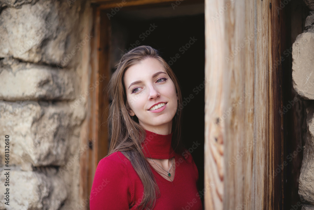 Fototapeta premium Young girl stands near the old door of ancient tower.