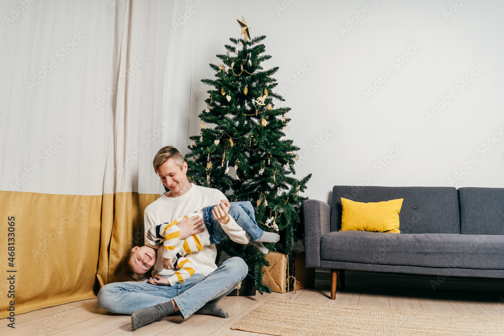 Obraz premium Happy dad tickle son near christmas tree