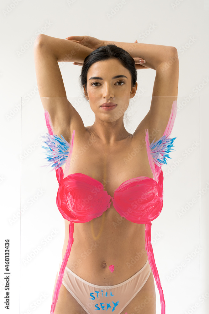 Fototapeta premium Serious woman standing over glass with drawing hairy unshaven female armpits