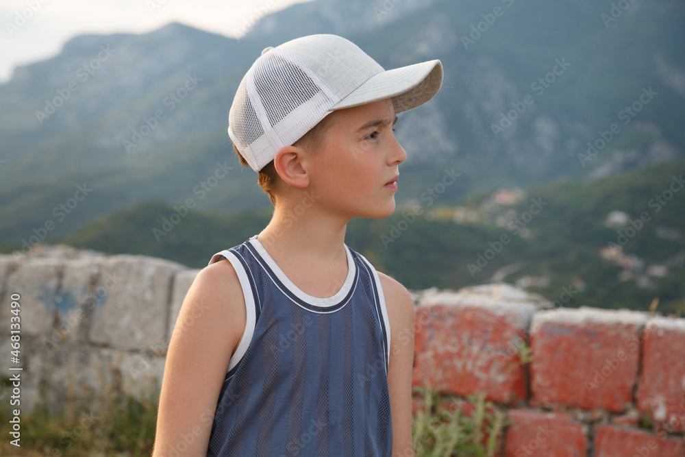 Cute boy in a cap on a background of mountains on a journey.