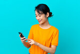 Young Vietnamese woman isolated on blue background sending a message or email with the mobile