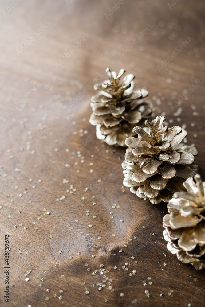 natural golden cones on a wooden table with gold spangles in the shape of stars. the concept of Christmas