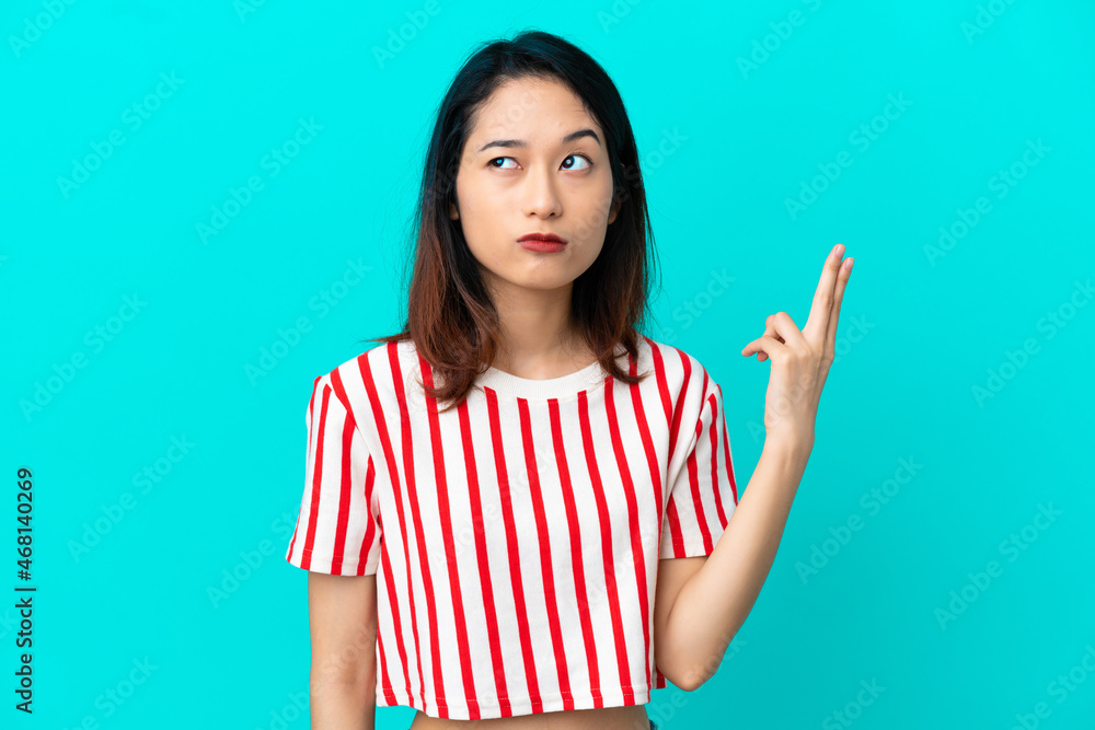 Young Vietnamese woman isolated on blue background with problems making suicide gesture Young Vietnamese woman isolated on blue background with problems making suicide gesture