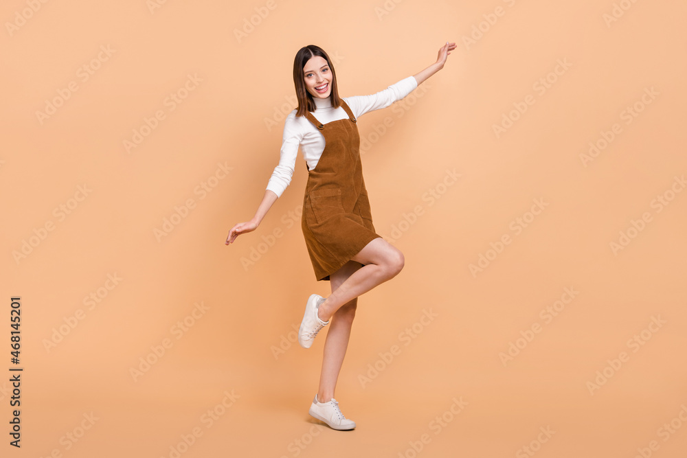 Full length body size view of attractive cheerful girl dancing having fun good mood isolated over beige color background Full length body size view of attractive cheerful girl dancing having fun good mood isolated over beige color background