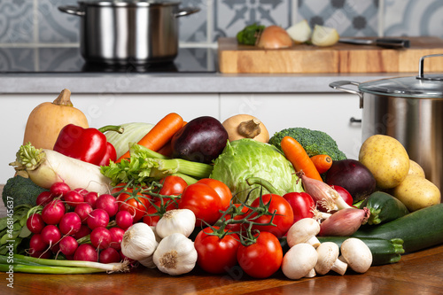A set of organic vegetables on the kitchen table and a stove in the background