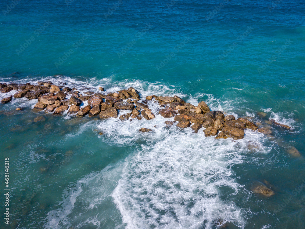 Aerial view of sea waves crashing of big stones