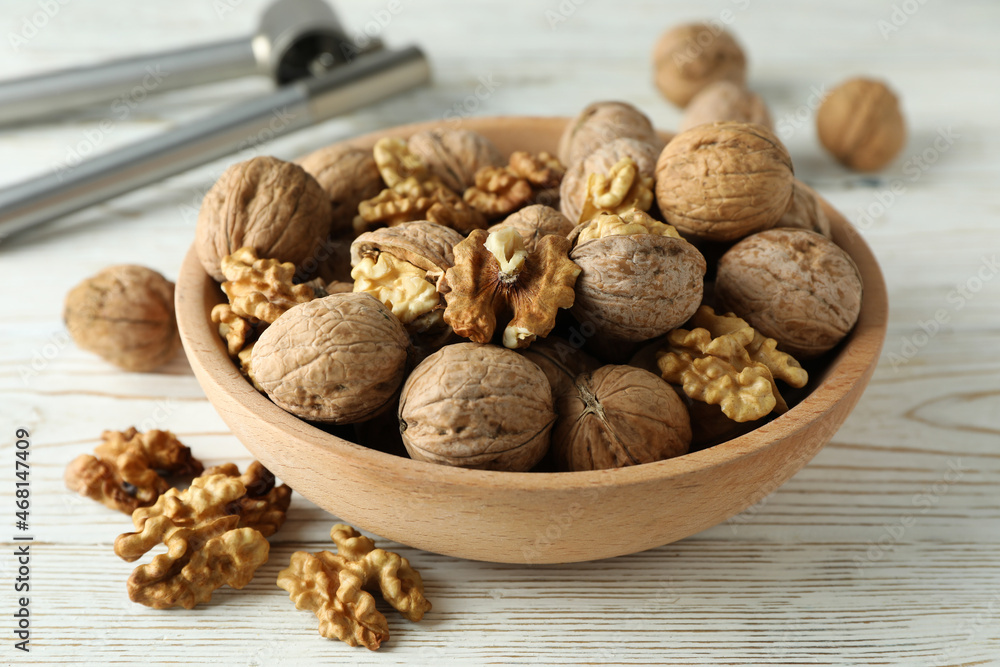 Nutcracker and bowl of walnuts on white wooden background Nutcracker and bowl of walnuts on white wooden background