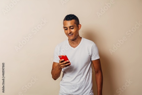 Young latin american man using a mobile phone over background.