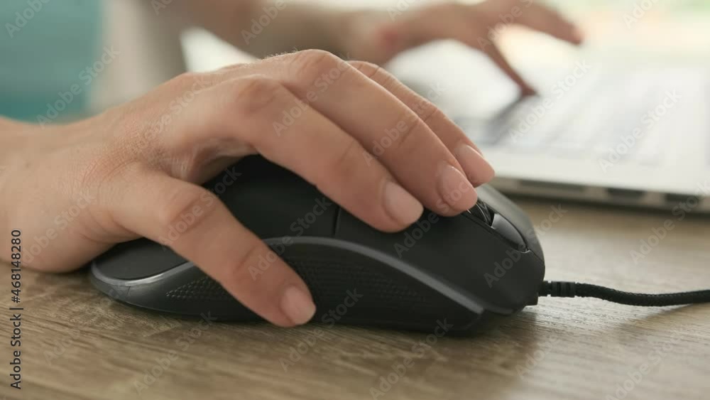 Hands using mouse and typing on laptop keyboard. Closeup view of person working with keypad Hands using mouse and typing on laptop keyboard. Closeup view of person working with keypad