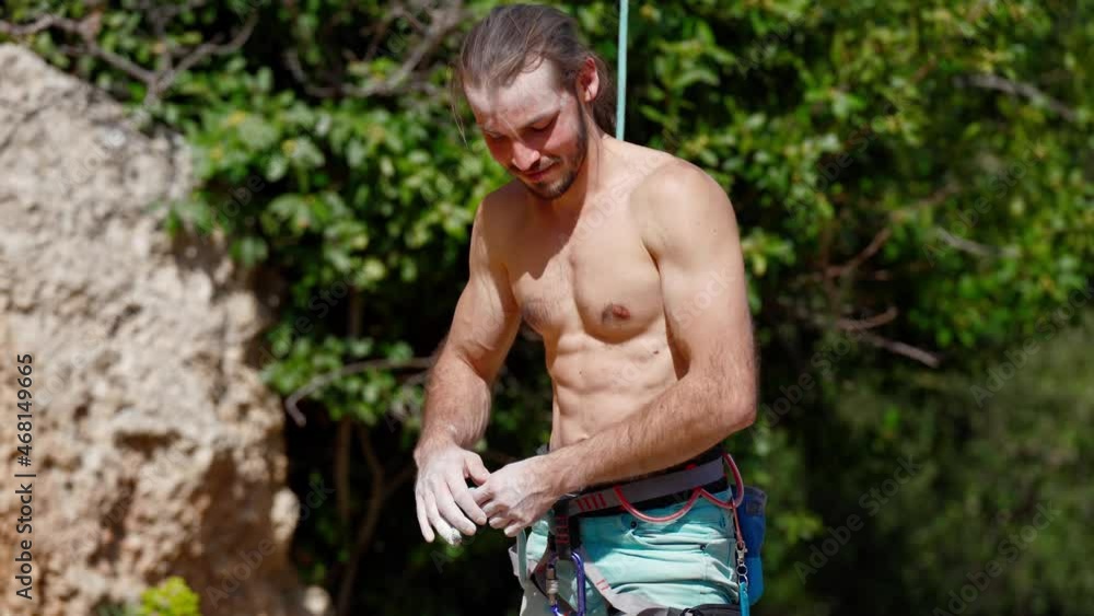 athletic Man confident after rock climbing cliff, proud of his achievement. rock climber with beautiful strong muscular body unties rope from climbing harness athletic Man confident after rock climbing cliff, proud of his achievement. rock climber with beautiful strong muscular body unties rope from climbing harness