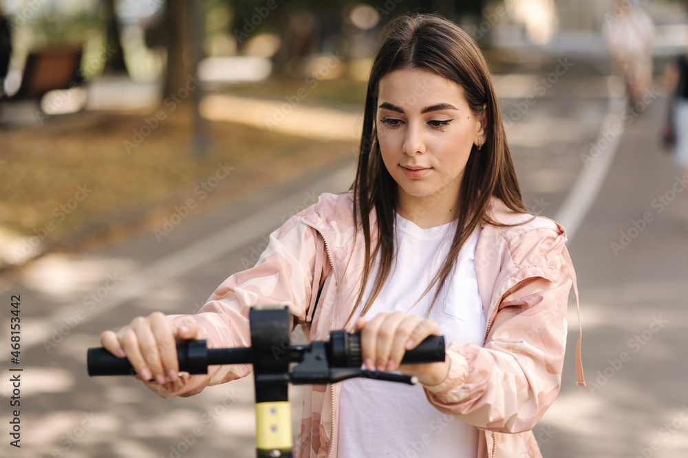 Young woman riding an electric scooter on a meeting. Ecological transportation concept. Attractive female outdoors with e-scooter Young woman riding an electric scooter on a meeting. Ecological transportation concept. Attractive female outdoors with e-scooter