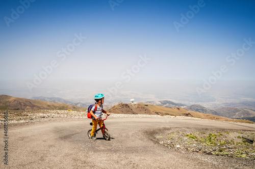 Small boy riding uphill on his first bicycle in Sierra Nevada mountains, Spain