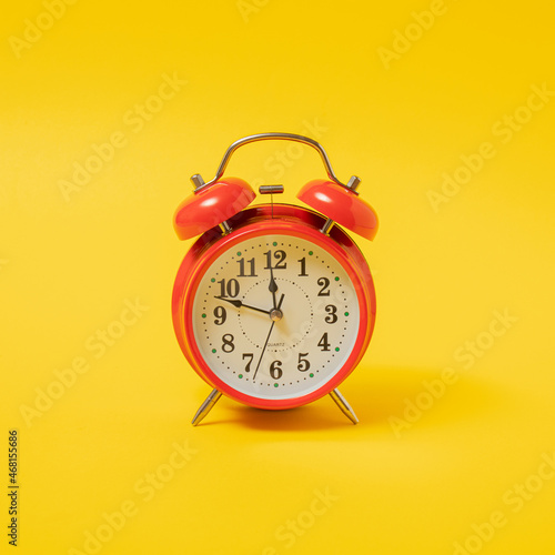 old red vintage table clock against yellow illuminating background with shadow. Retro Christmas abstract art with copy space