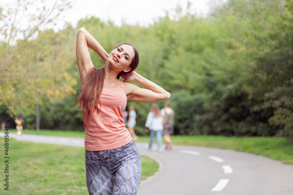 Woman runner stretching arms before running summer park