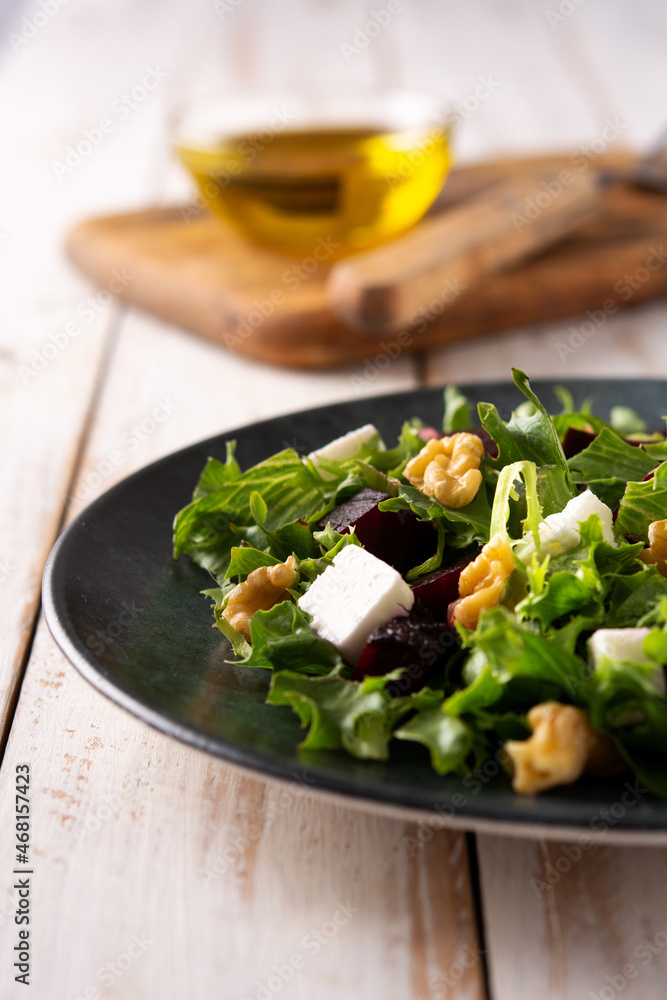 Beetroot salad with feta cheese,lettuce and walnuts on white wooden background