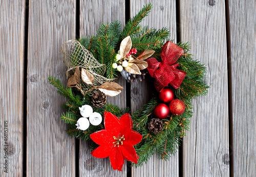 Christmas wreath decorated with red balls, lights and pinecones on a wood background photo